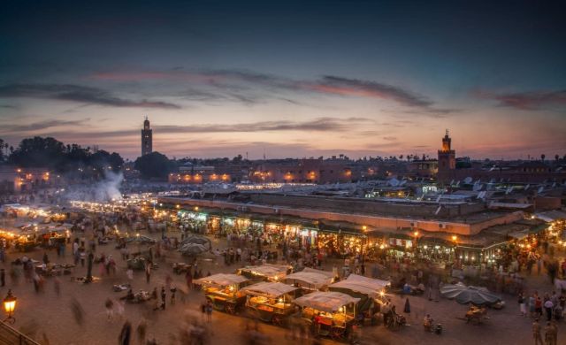 Aerial view of Jemaa el-Fna square in Marrakech at sunset with smoke from food stalls and the Koutoubia Mosque in the background