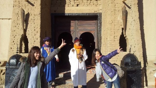 Japanese travelers enjoying a Morocco desert tour outside Auberge du Sud in Merzouga