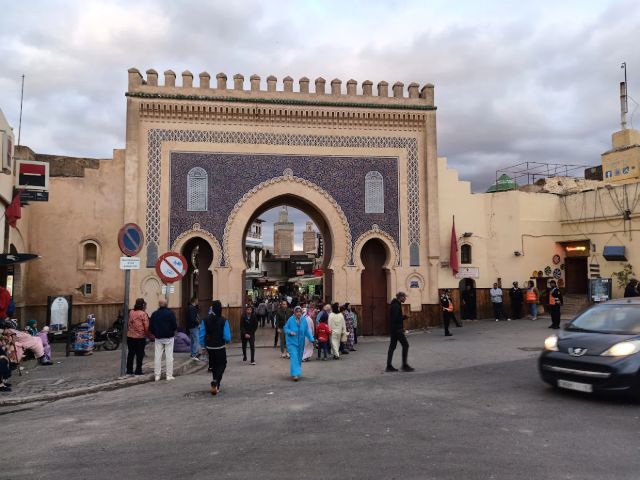 Bab Bou Jeloud gate in Fes, Morocco, with visitors entering the historic medina through traditional Moroccan architecture.