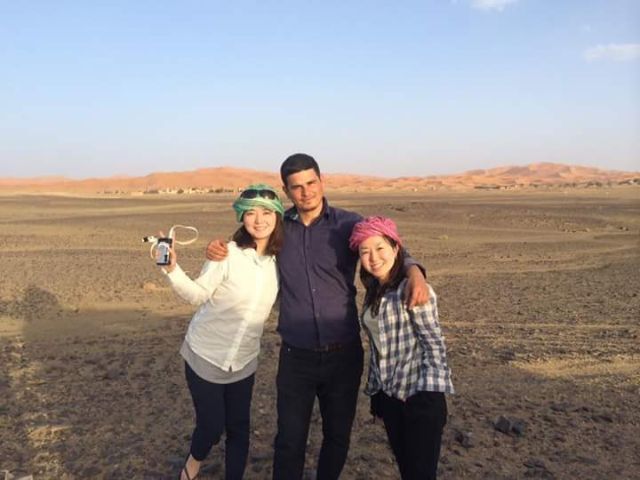 Local guide with two smiling travelers in the Sahara desert near  Merzouga