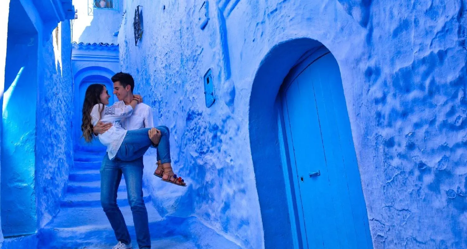 Honeymoon couple walking through the blue streets of Chefchaouen, Morocco, surrounded by traditional blue-painted walls and doors.