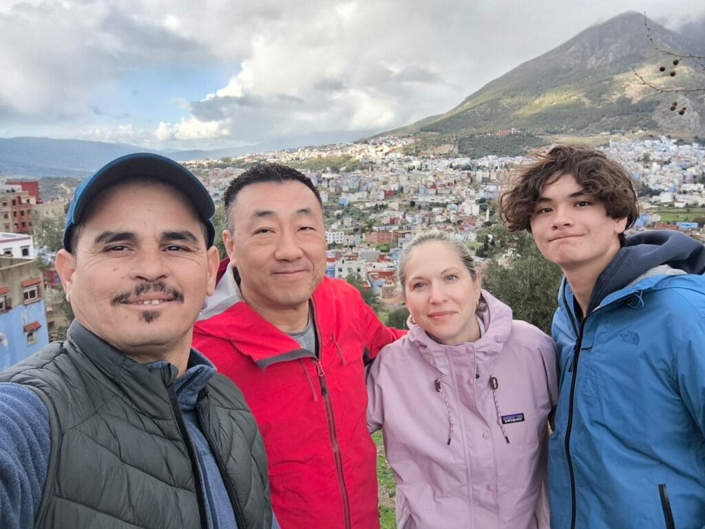 Canadian travelers posing with their guide driver Sabir overlooking the blue city of Chefchaouen in Morocco