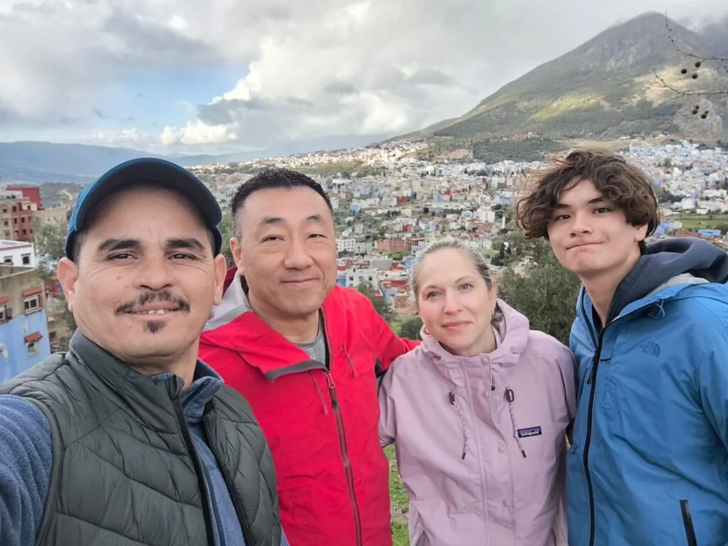 Canadian travelers posing with their guide driver Sabir overlooking the blue city of Chefchaouen in Morocco