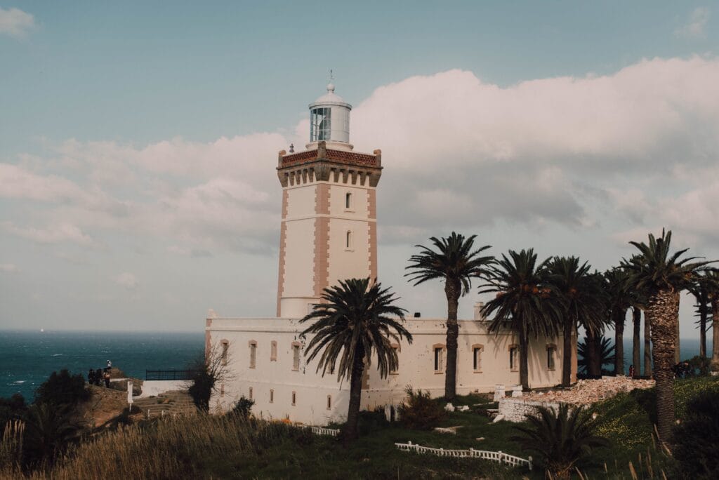 Historic lighthouse standing on the rugged coastline of Tangier, Morocco, overlooking the meeting point of the Atlantic Ocean and the Mediterranean Sea, with dramatic rocky cliffs and deep blue waters stretching to the horizon.