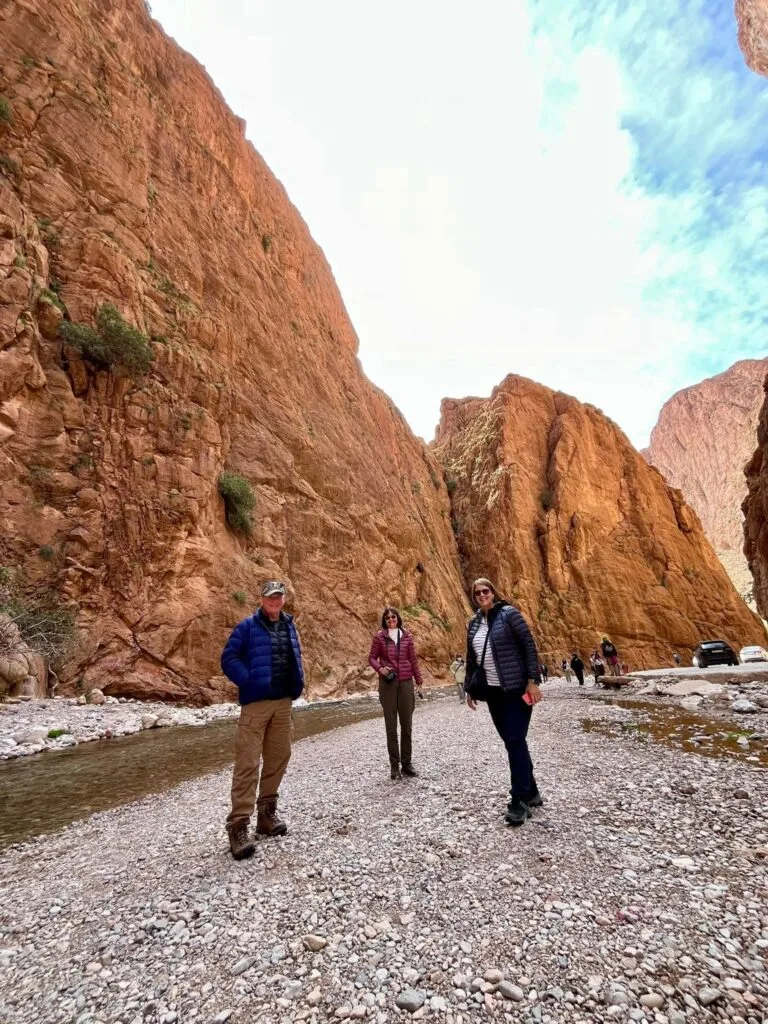 Tourists walking between the dramatic red cliffs of Todra Canyon in Morocco.