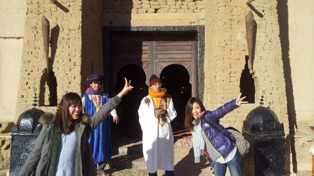 Japanese travelers enjoying a Morocco desert tour outside Auberge du Sud in Merzouga