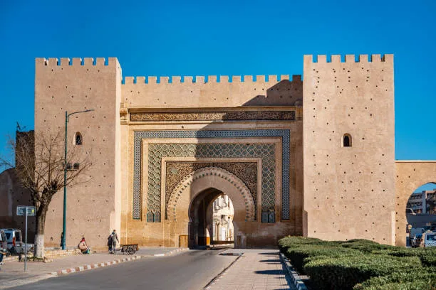 Historic gate in Rabat, Morocco featuring traditional tilework and architectural details under a clear blue sky.