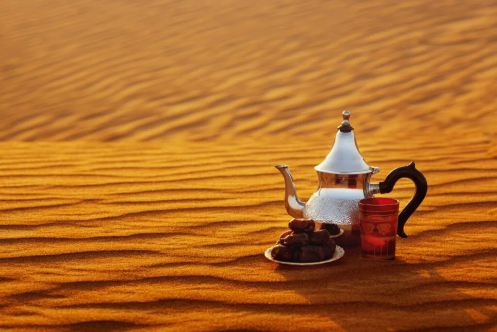 Traditional Moroccan teapot on golden Sahara dunes at sunset