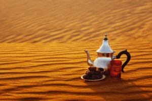 Traditional Moroccan teapot on golden Sahara dunes at sunset