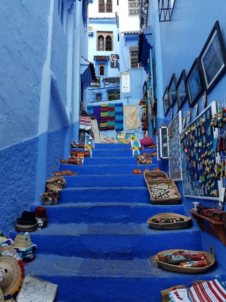Narrow winding streets and whitewashed buildings painted in vivid shades of blue in the medina of Chefchaouen, a iconic mountain town nestled in the Rif Mountains of northern Morocco.