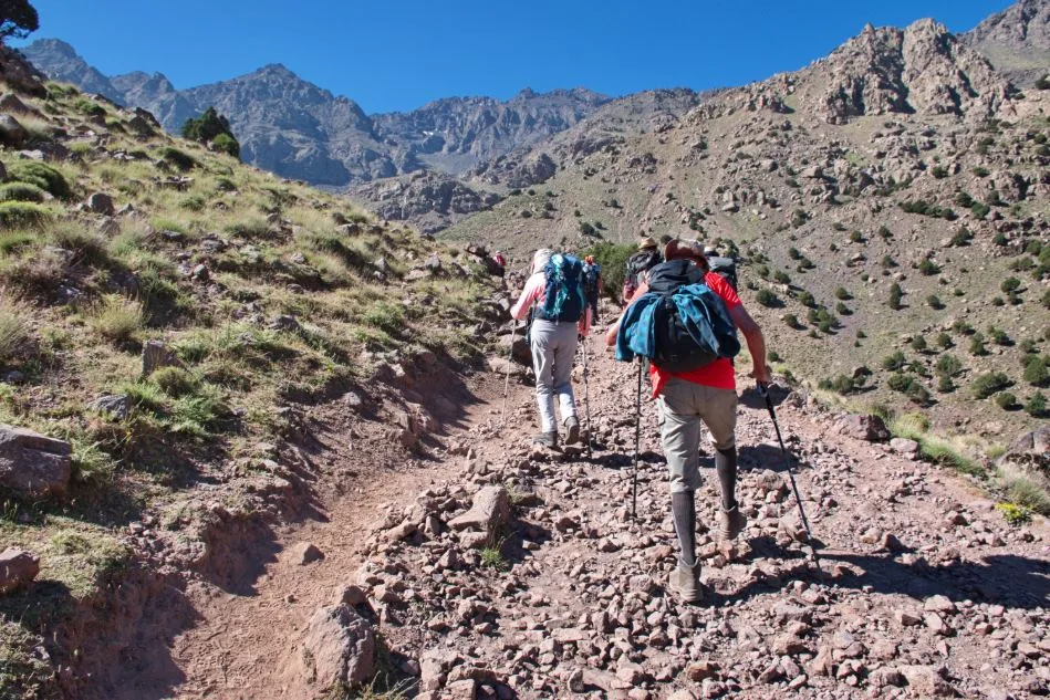 Travelers trekking through scenic mountain trails in the High Atlas Mountains of Morocco.